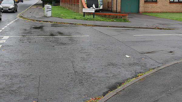 A side road junction on Winchester Road with no drop kerb or tactile paving for pedestrians to cross