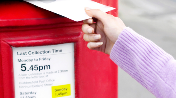 Person posting an envelope into a postbox